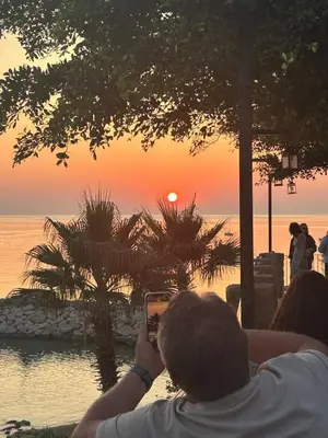 a man taking a picture of the sunset with his cell phone at Terra Vista in Kérynia