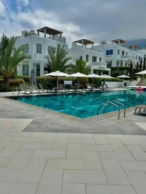 a swimming pool with chairs and umbrellas in front of a building at Terra Vista in Kérynia