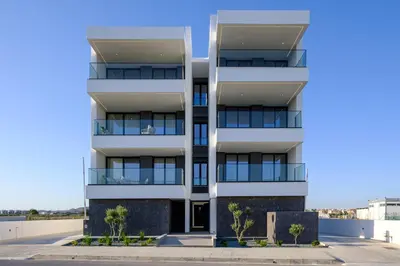 a white apartment building with trees in front of it at Artemis 202 - Seaside Stories in Livadhia