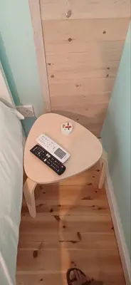 a small table next to a bed with a remote control at Jay's Nest in Larnaka