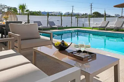 a pool with chairs and a table with wine glasses at Princess Anne Luxury Villa - Large Pool in Protaras