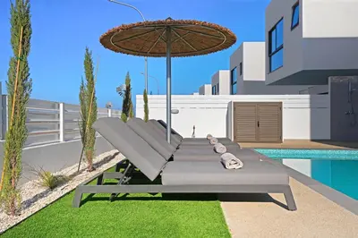 a table with an umbrella next to a pool at Princess Anne Luxury Villa - Large Pool in Protaras