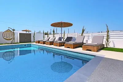 a swimming pool with lounge chairs and an umbrella at Princess Zena Luxury Villa - Large Pool in Protaras