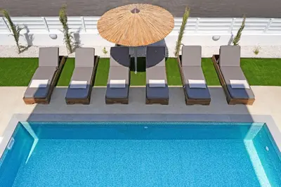 a group of chairs sitting next to a pool at Princess Zena Luxury Villa - Large Pool in Protaras