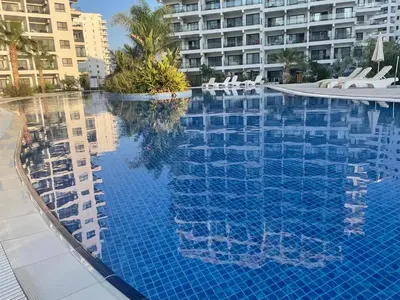 a large swimming pool with chairs and a building at Family friendly modern flat in Caesar Resort &SPA, Long Beach İSKELE, KKTC in Iskele