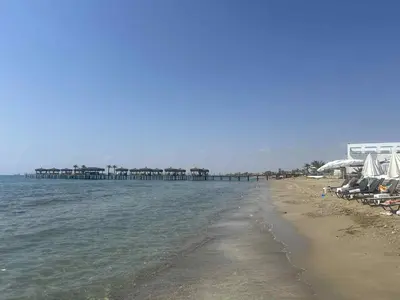 a beach with chairs and a pier in the water at Sunrise Beach Club, Bogaz, North Cyprus in Boğaz