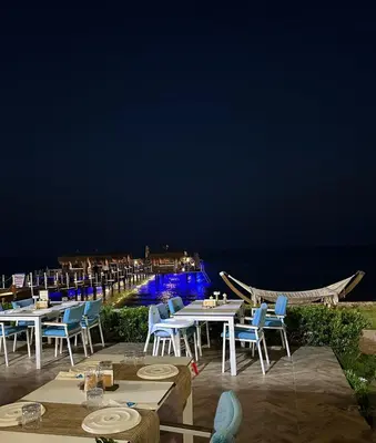 a restaurant with tables and chairs and the ocean at night at Sunrise Beach Club, Bogaz, North Cyprus in Boğaz