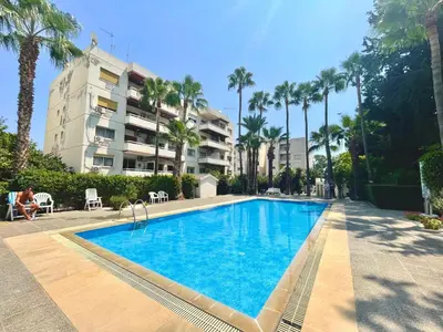 a swimming pool with palm trees and a building at Beach Front Apartment in Limassol