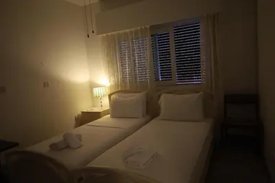 a bedroom with a bed with white pillows and a window at Beach Front Apartment in Limassol