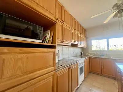 a kitchen with wooden cabinets and a microwave at Beach Front Apartment in Limassol