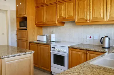 a kitchen with wooden cabinets and a white stove top oven at Beach Front Apartment in Limassol