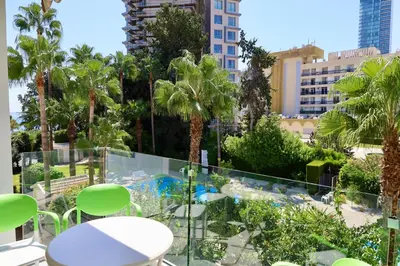a balcony with tables and chairs and palm trees at Beach Front Apartment in Limassol