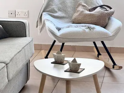 a living room with a chair and a table at Fresh & Cozy-close to the beach in Paralimni