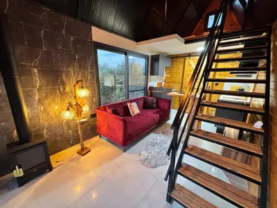 a living room with a red couch and a stone wall at Chardonnay Tiny Home for Nature Lovers North Cyprus in Kérynia