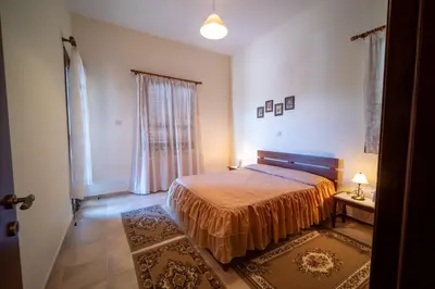 a bedroom with a bed and a table and a window at Casa Harmonia Traditional Stone House, Escape to Silence Soul and Serenity in Nature with 2 Bedrooms, Fireplace and Mountain Breeze in Mandria