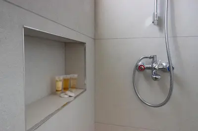 a shower in a bathroom with two glasses on a shelf at Sea View Stay 200m to Beach in Voroklini