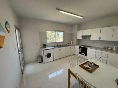 a large kitchen with white cabinets and a table and a tableablish at Sfina Sea view apartment by Ezoria villas in Limassol
