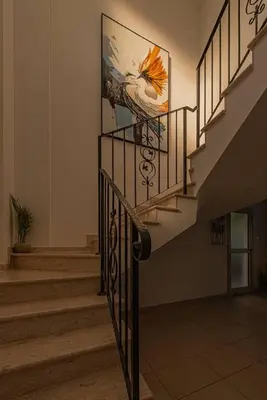 a staircase with a painting of a chicken on the wall at TelMar Royal Villa Sea View in Mazotos