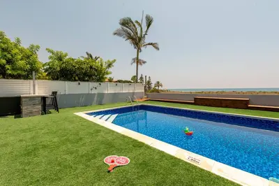 a swimming pool with toys in the grass near the ocean at TelMar Royal Villa Sea View in Mazotos