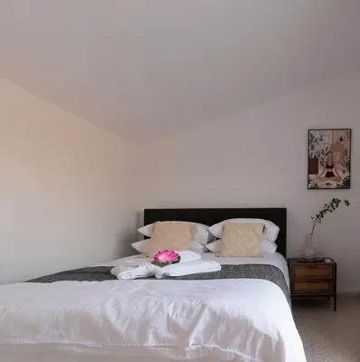 a bed with white sheets and pink flowers on it at TelMar Larnaca 