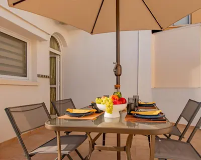 a table with a bowl of fruit and an umbrella at TelMar Larnaca 