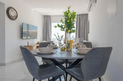 a dining room table with chairs and a clock on the wall at TelMar Sea View - 2 min walk to the Beach in Voroklini