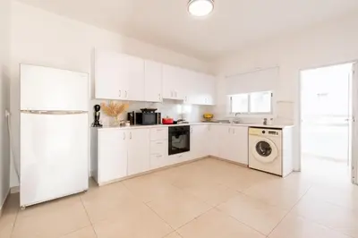 a kitchen with white cabinets and a washer and dryer at TelMar City - Harbour Sea View from the Veranda in Larnaka
