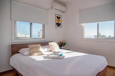a bedroom with a white bed with two windows at TelMar City - Harbour Sea View from the Veranda in Larnaka