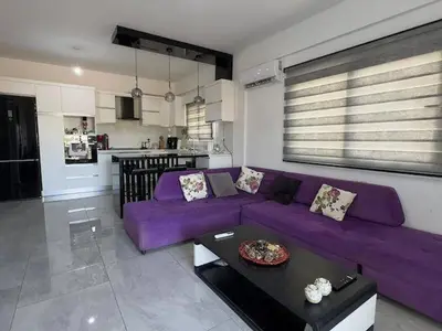 a living room with a purple couch and a kitchen at Modern apartment in North Nicosia