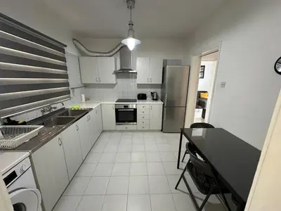 a kitchen with white cabinets and a stainless steel refrigerator at Suite 52 - Two Bedroom Apartment with Shared Pool in Nicosia