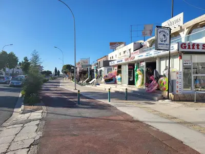 an empty street in a town with shops at Chryso Apts Protaras in Paralimni