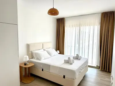 a bedroom with a bed with white sheets and a window at Bohemian penthouse in Girne Alsancak, close to Merit hotels in Kérynia