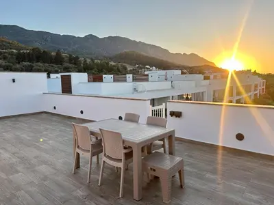 a table and chairs on a balcony with the sunset at Bohemian penthouse in Girne Alsancak, close to Merit hotels in Kérynia