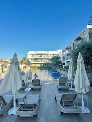 a pool with chairs and umbrellas next to a building at Bohemian penthouse in Girne Alsancak, close to Merit hotels in Kérynia