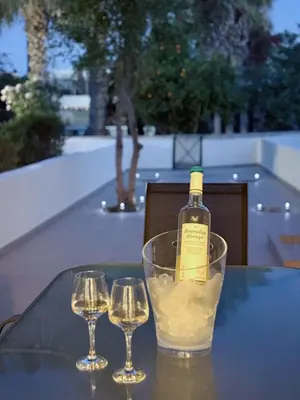 a bottle of wine and two wine glasses on a table at 5-Min Walk to Beach - Bright 2-BR Home with Private Garden & Sunset Views in Voroklini