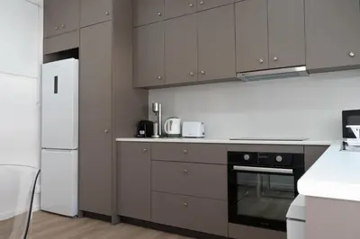 a kitchen with brown cabinets and a white refrigerator at Limassol Sunbliss by Staycom in Limassol