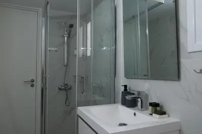 a bathroom with a sink and a shower with a mirror at Limassol Sunbliss by Staycom in Limassol