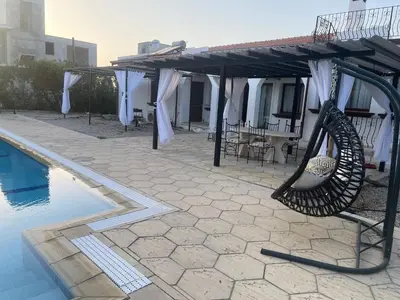a patio with a hammock next to a swimming pool at A Spacious Villa to Entertain in Aglantzia