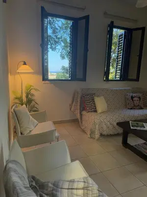 a living room with a couch and two windows at Tranquil Poolside apartment with stunning views in Mazotos