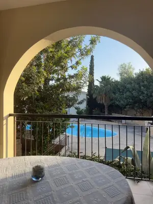 a view of a swimming pool from a balcony at Tranquil Poolside apartment with stunning views in Mazotos