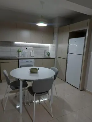a kitchen with a table and chairs and a white refrigerator at Bird's Nest, close to EMU, in the city center in Dherinia