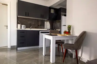 a kitchen with black cabinets and a white table and chairs at Apartment Northern Cyprus