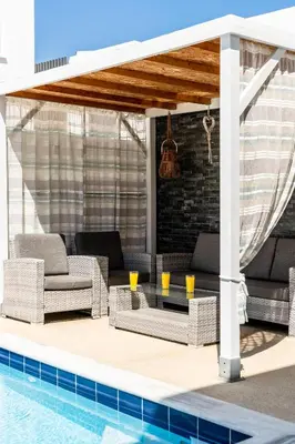 a patio with wicker furniture next to a swimming pool at Villa Alassia 16 by Ezoria Villas in Paralimni