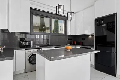 a kitchen with white cabinets and a washer and dryer at Villa Alassia 16 by Ezoria Villas in Paralimni