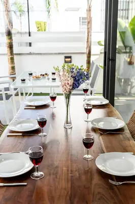 a table with glasses of wine and a vase of flowers at Villa Alassia 16 by Ezoria Villas in Paralimni