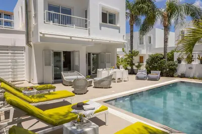 a villa with a swimming pool with yellow lounge chairs at Protaras Seaside Villa Narcissos 16 in Protaras