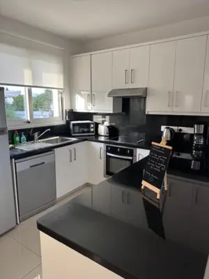 a kitchen with white cabinets and a black counter top at Villa Samantha in Paralimni