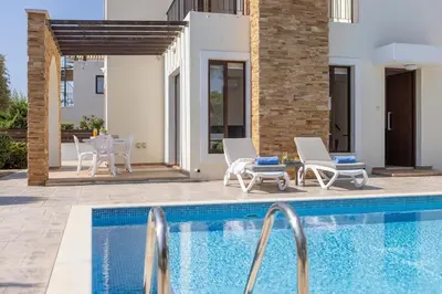 a swimming pool with chairs and a house at Ionion H30 in Ayia Napa