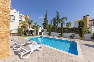 a swimming pool with two lounge chairs next to a house at Ionion H30 in Ayia Napa