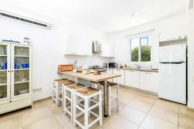 a kitchen with white cabinets and a counter with stools at Villa Atlantis in Protaras